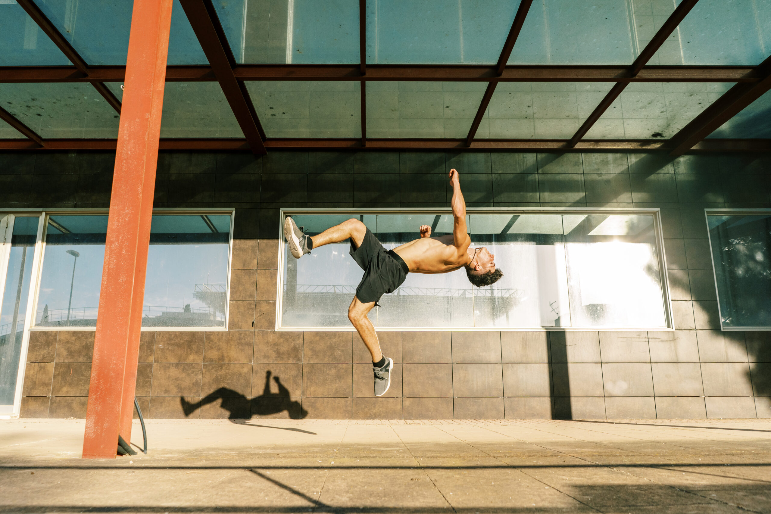 Agile sportsman doing back jump trick on street